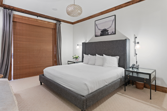 A spacious bedroom in Grand Lodge Four Bedroom 306 with a king-sized bed, bedside table, a large window with a view of the mountains, and a plush carpet.