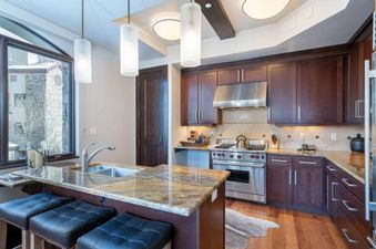 The kitchen in Lumiere One Bedroom Standard Residence features stainless steel appliances, granite countertops, and a breakfast bar with seating.