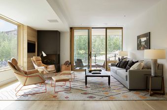 A modern and inviting living room in the Caldera House Two Bedroom Suite with comfortable seating, a fireplace, and a view of the outdoors.