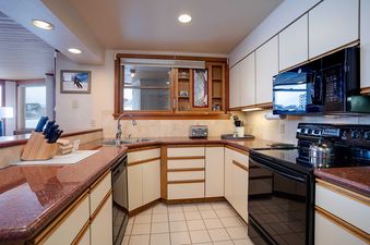 The fully equipped kitchen at Chateau Chamonix CX114 features white cabinets, granite countertops, and modern black appliances including a stove, microwave, and dishwasher.
