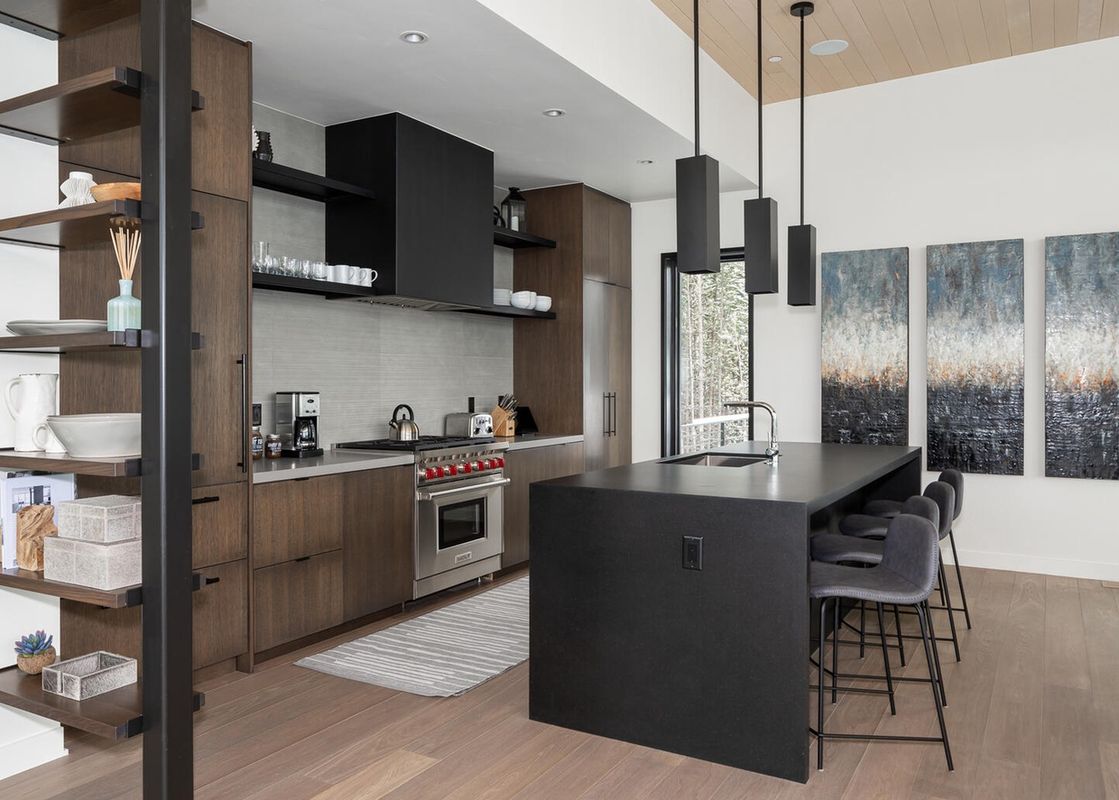 The modern kitchen at Moonlight Basin 5 Thistle Way features dark wood cabinets, stainless steel appliances, and a large island with bar seating.