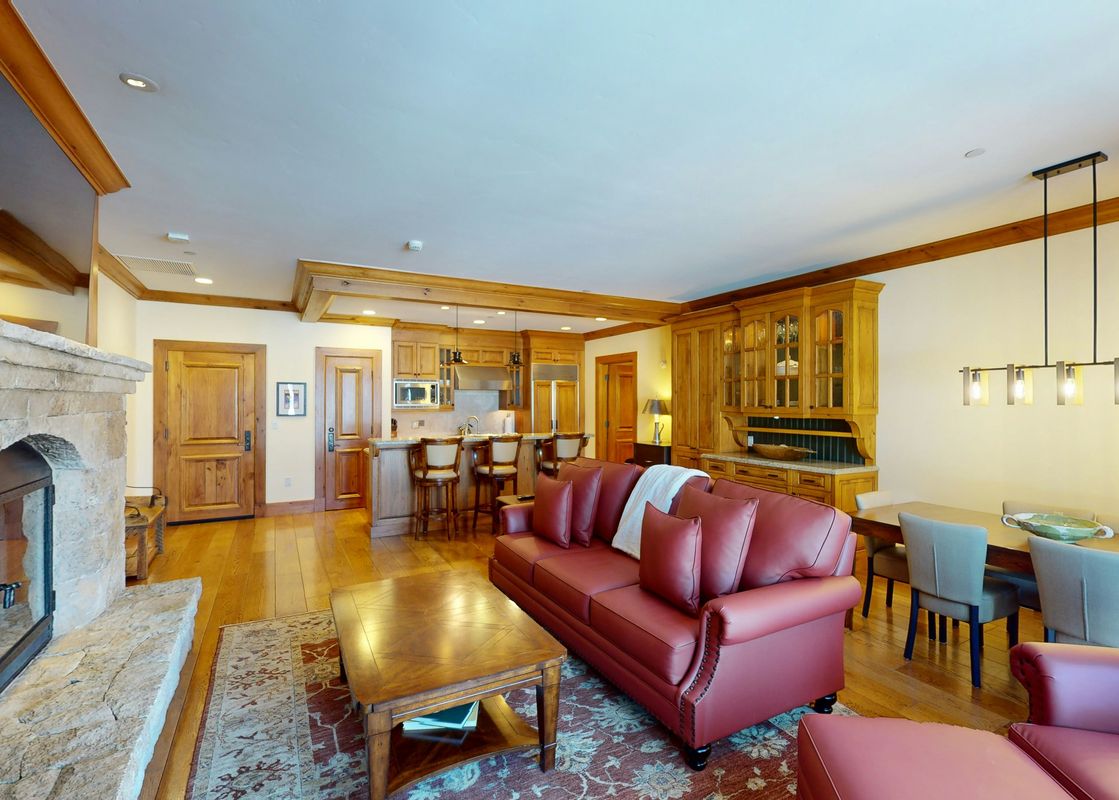 The living room of Top of the World at Bachelors Gulch features a fireplace, a leather sofa, a coffee table, and a dining table with chairs.