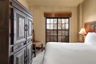 A cozy bedroom with a large wooden armoire, a comfortable bed, and a window offering a view of the outdoors.