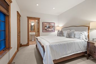 A serene bedroom at Silver Creek Lodge with a large bed, elegant wooden furnishings, and a glimpse into an adjoining private bathroom.
