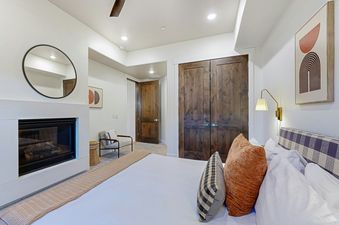 A modern and cozy bedroom in Blackstone 105 with a fireplace, elegant bedding, and contemporary decor.