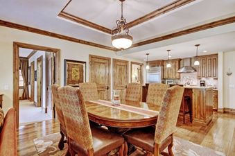 A formal dining room with a large wooden table and chairs, connected to a modern kitchen.
