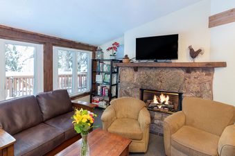 The cozy living room of Manitou Lodge 1 Hotel Room Bronze Rated features a stone fireplace and comfortable seating.