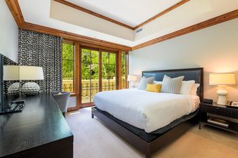 A bedroom with a king-size bed, nightstands, and a large window with a view of trees.