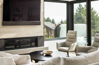 Canyons Edge features a spacious living area with a fireplace, a large TV, a plush sectional sofa, and access to a balcony overlooking the lush green landscape.