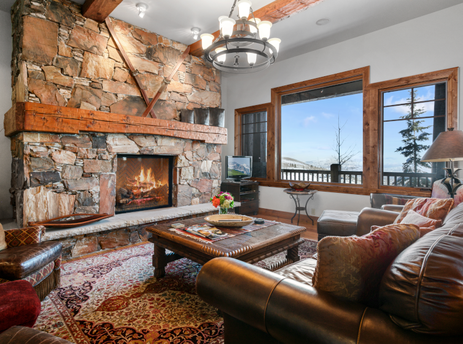 Spacious living room in Grand Lodge Three Bedroom Deluxe 206 with a fireplace and large windows with mountain views.