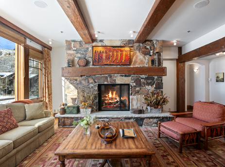 A living room in Grand Lodge Three Bedroom Deluxe 404 with a stone fireplace, a large sofa, and a coffee table in front of it.