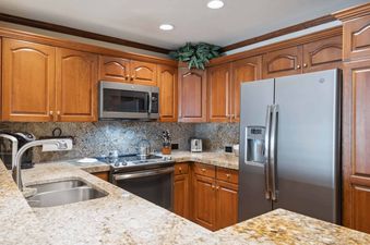 The kitchen at St James Place 218 features stainless steel appliances, granite countertops, and wooden cabinetry.