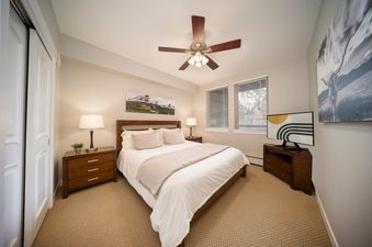 The bedroom in Fraser Crossing 3509 features a comfortable bed, bedside tables with lamps, a ceiling fan, and a flat-screen TV.