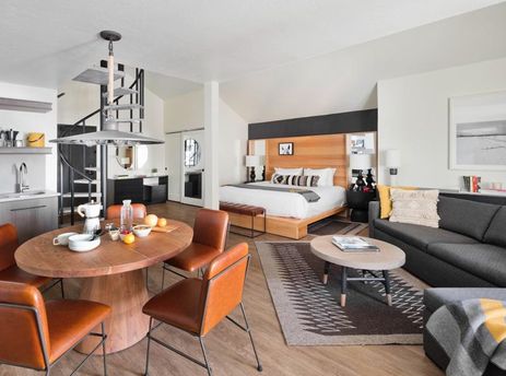 Modern open-concept living area with a dining table, sofa, and bed in the Gravity Haus JH Premium Loft Suite.