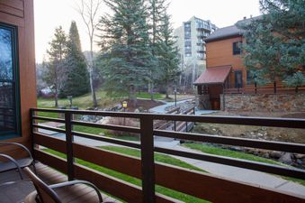 Private balcony view at Kutuk 112 looking out over a paved path, evergreen trees, and resort buildings.