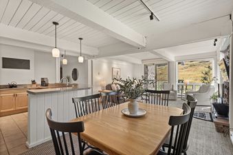 The great room at Enclave 209 featuring a combined kitchen, dining area, and living space with large windows overlooking a grassy mountain.