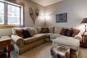 A view of the ceiling of EagleRidge Townhomes 1516, showing a living room with a large sectional sofa and two lamps, one of which is hanging from the ceiling.