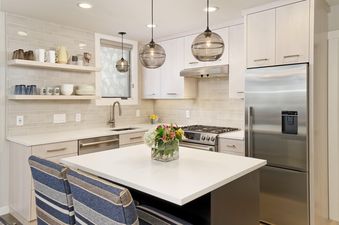The contemporary kitchen in Tamarack 04 features light wood cabinetry, stainless steel appliances, and a white island with pendant lighting.
