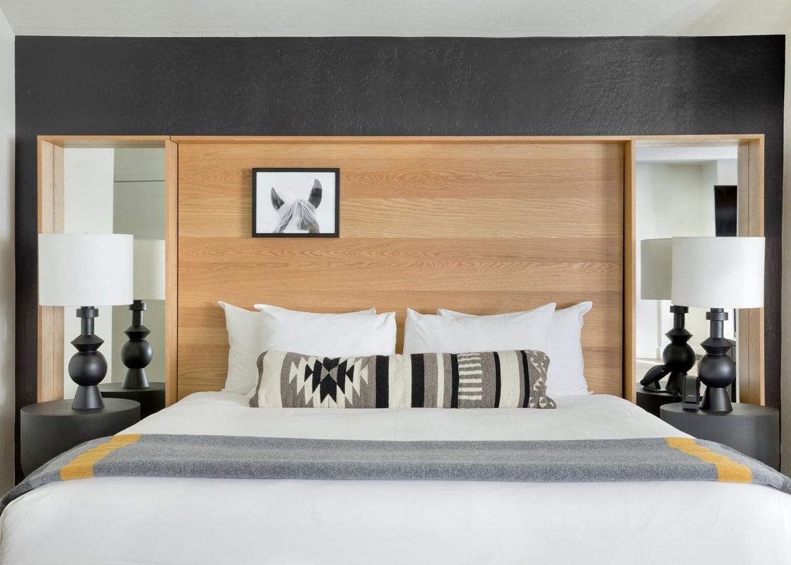 A modern king bed with a wood paneled headboard in the Gravity Haus JH King.