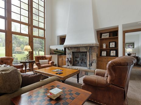 A warm and inviting living room at 193 Enclave featuring a stone fireplace and comfortable leather chairs.