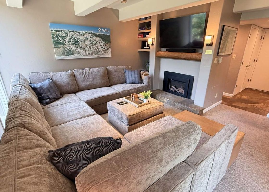 The living area of Vail International 002 features a large sectional sofa, a fireplace, and a large flat-screen TV.