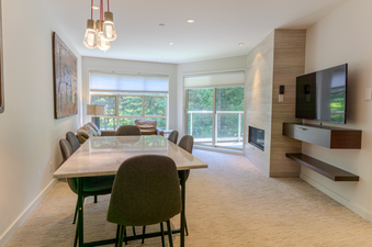 The dining area and living room with a fireplace and television at Aspens on Blackcomb Unit 451.