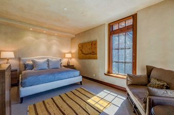 A serene bedroom in See Forever San Sophia 116 with a light blue bed, wooden accents, and sunlight streaming through a large window.