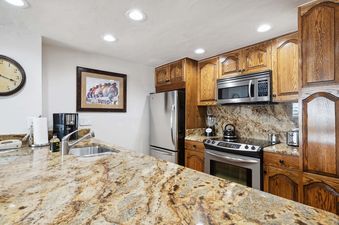 The inviting kitchen in Lodge Tower 678 features granite countertops and wooden cabinetry.