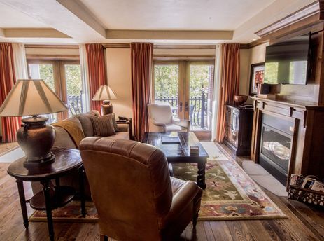 The living area of the Hyatt 2 Bedroom Premium features a comfortable sofa, chairs, a coffee table, and a fireplace, with natural light streaming in through balcony doors.