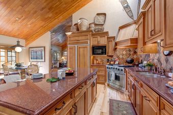 A kitchen with wood cabinets and a large island, the room is decorated with a rustic theme.