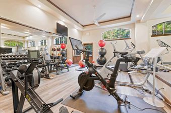 Well-equipped fitness center at St James Place 310 with Peloton bike, row machine, and free weights.