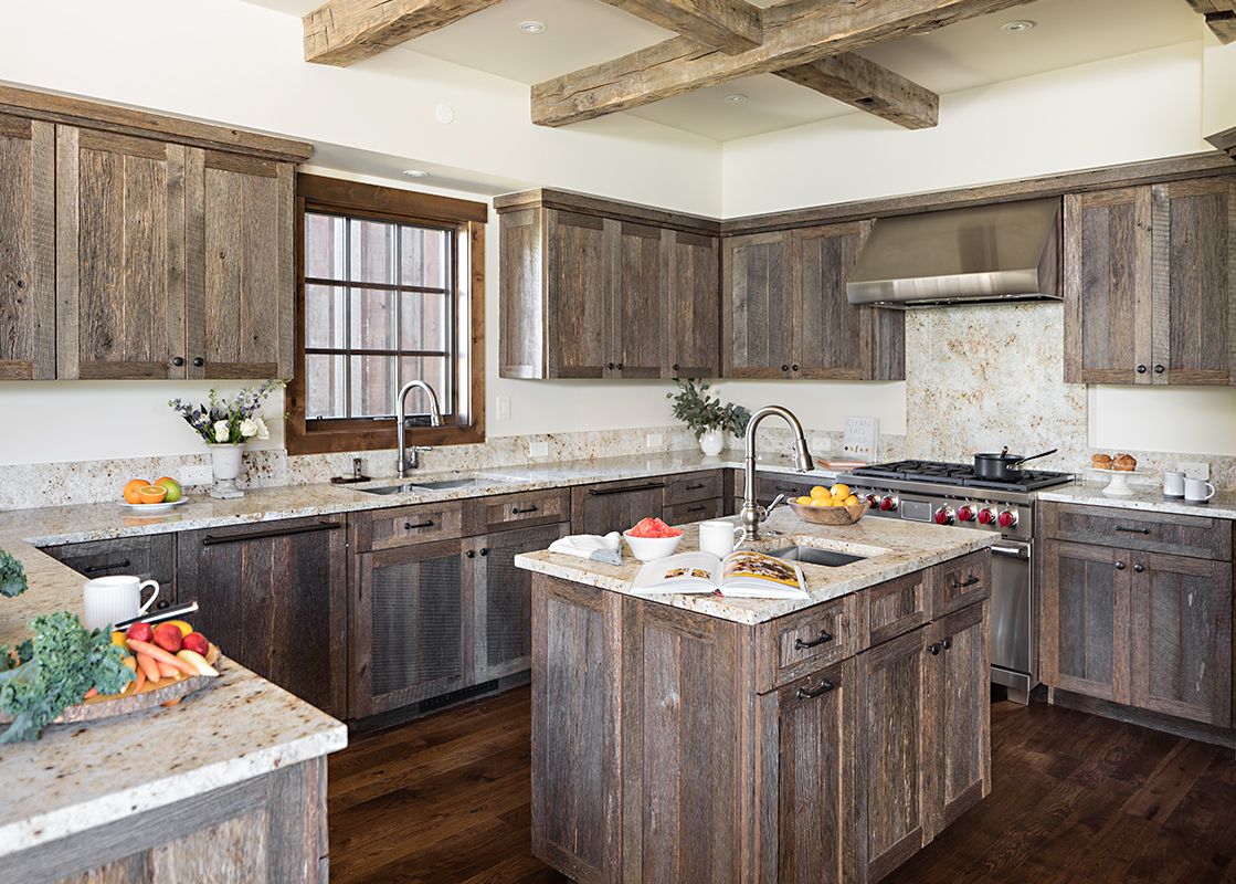 A rustic yet modern kitchen with distressed wooden cabinetry, granite countertops, and a central island with a sink.