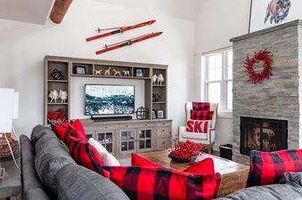 Moonlight Basin Saddle Ridge D1 living room with fireplace, large TV, and a comfortable sofa with red pillows.