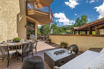 A luxurious outdoor patio featuring a fire pit, dining table, and comfortable seating, all with mountain views at Sunstone Chalet at One Beaver Creek.