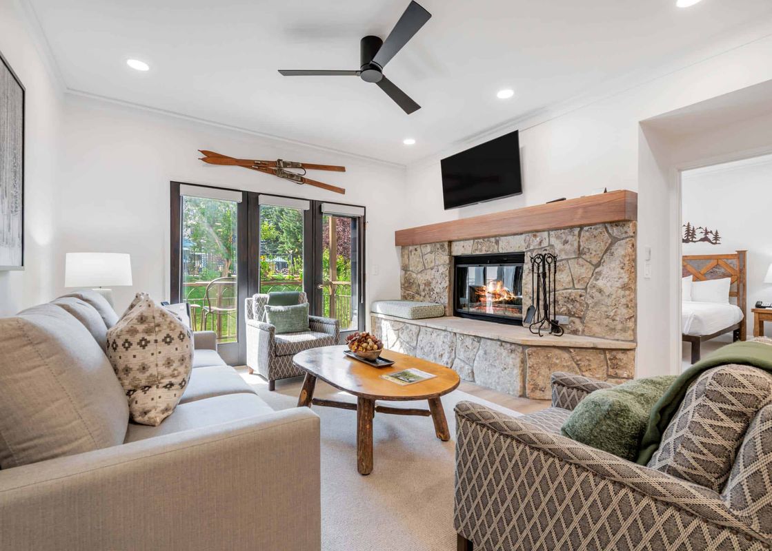 A cozy living room at The Charter E1305 featuring a fireplace, comfortable seating, and large windows with a view of the outdoors.