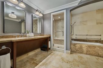 A spacious and elegant bathroom featuring a double vanity, a large walk-in shower, and a luxurious bathtub.