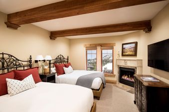 A cozy bedroom with two queen beds, a fireplace, and a flat-screen TV.