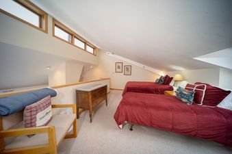 A cozy bedroom with two beds, each adorned with deep red comforters and an assortment of decorative pillows.