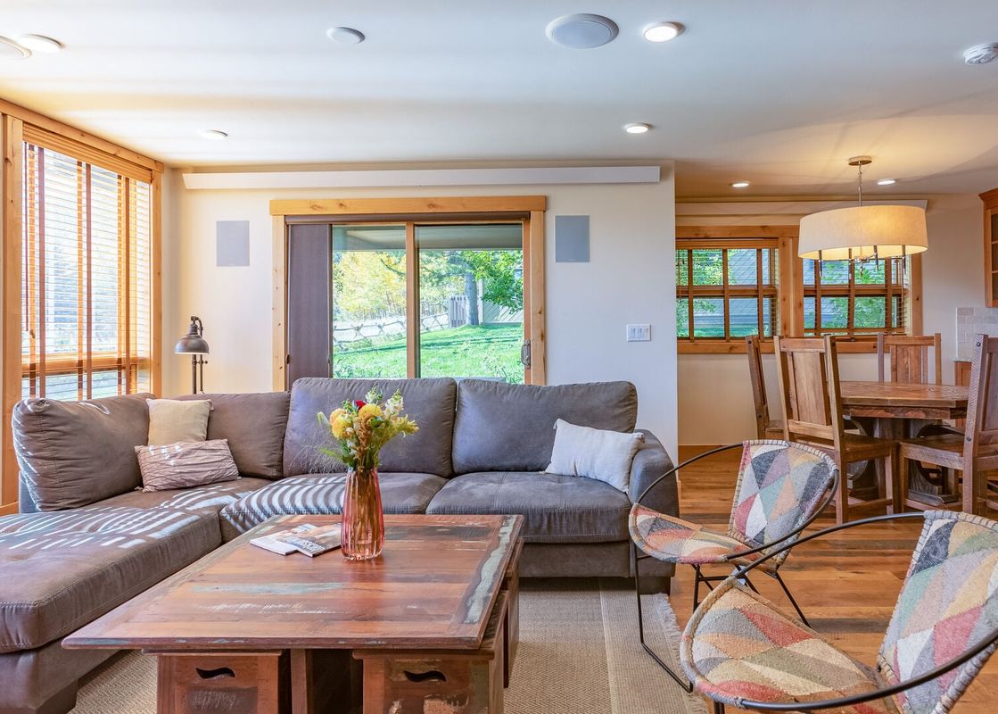 Living area in Nez Perce A2 with a gray sectional sofa, rustic wooden coffee table, and adjacent dining set.