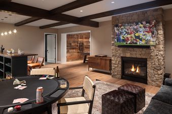 A cozy entertainment area at the Northern Hideaway featuring a stone fireplace, a large TV, a poker table, and a bar area.