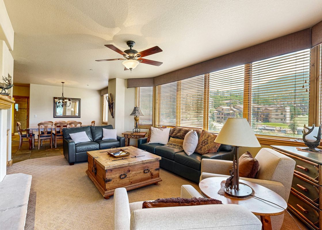 The living area within Torian Plum Creekside 519 features comfortable seating, a fireplace, and a dining area, with large windows overlooking the scenic outdoors.