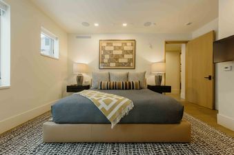 A luxurious bedroom at Transfer Haus, showcasing a king-size bed with elegant bedding, sophisticated lighting, and a tasteful abstract artwork.