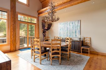 Moonlight Basin Penthouse 3 features a large dining room with a round wooden table, chairs, and a chandelier.