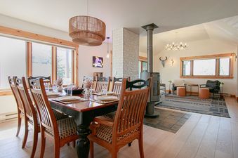 Dining area with wooden table, chairs, modern fireplace, and living room in Teewinot B4.