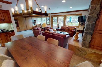 Dining area in Manor Vail 139 with large wooden table, chairs, and access to living room.