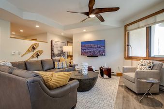 A cozy and inviting living room at Chateau Chamonix CX332 with a large L-shaped leather sofa, a round wooden coffee table, and a wall-mounted TV displaying a mountain scene.
