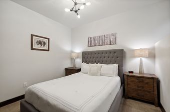 A cozy bedroom at 2nd Street Lofts 209 with a queen bed, two nightstands, lamps, and nature-themed artwork.