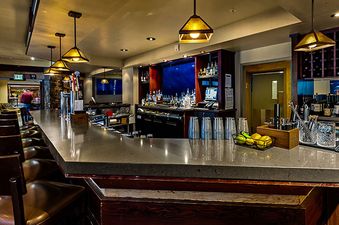 The Steamboat Grand Deluxe King features an elegant, inverted bar area, showcasing unique design and sophisticated lighting, along with a well-stocked wine rack.