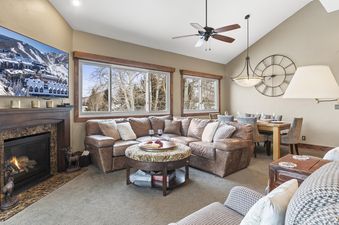 Living room with a fireplace, couch and a dining area with a large clock.