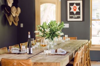 The rustic wooden dining table in Silver Queen Chalet seats guests around an antique wooden table under a stunning chandelier.